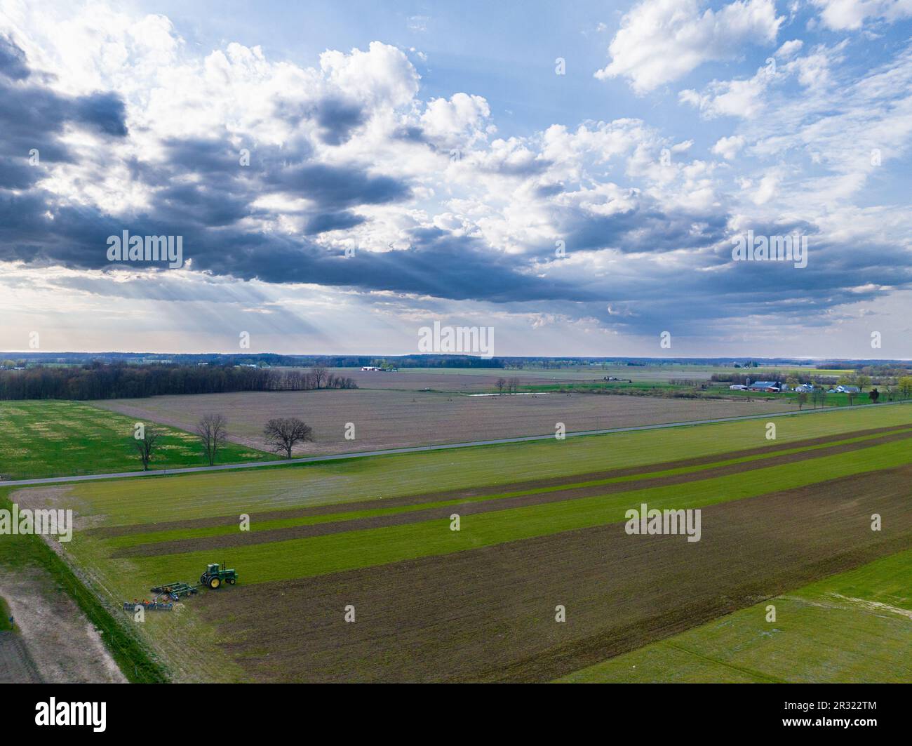 Paesaggio accattivante: Trattore che tilla il campo sotto un cielo pittoresco. Foto Stock