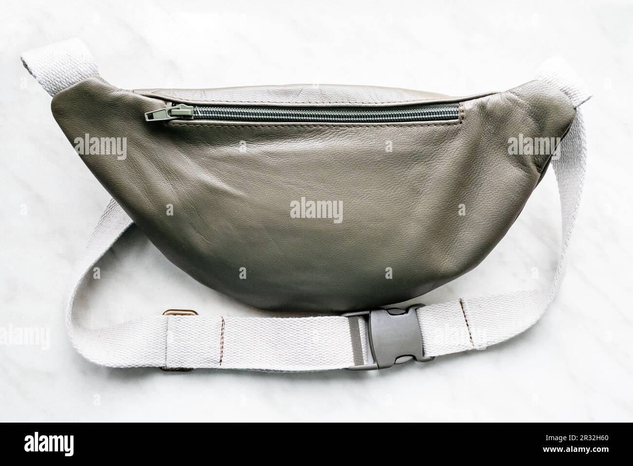 lato posteriore della borsa da cintura verde in pelle chiusa sul bordo grigio primo piano Foto Stock