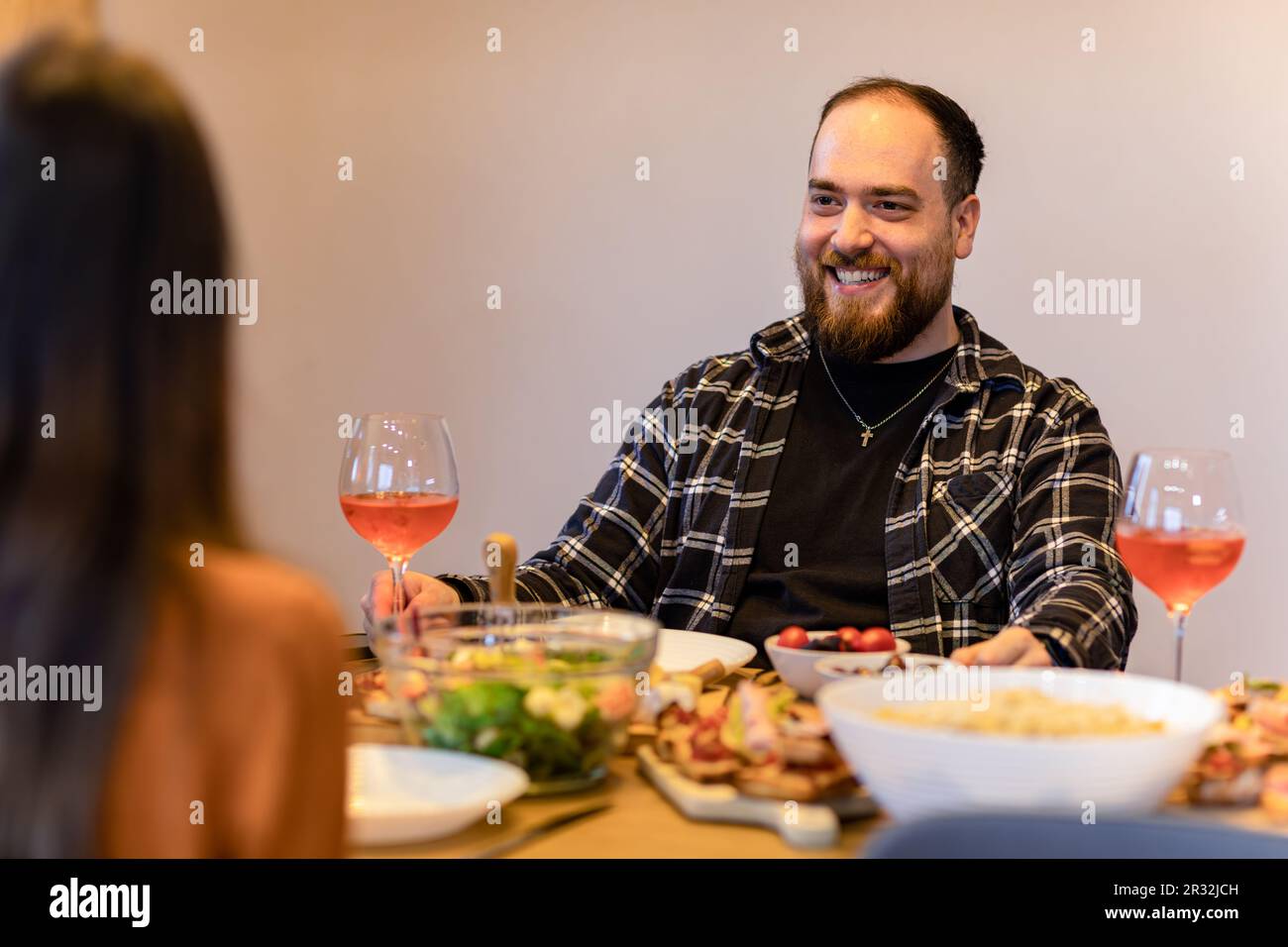 Coppia gustando la cena e il vino, l'attenzione è su un uomo sorridente. Foto Stock
