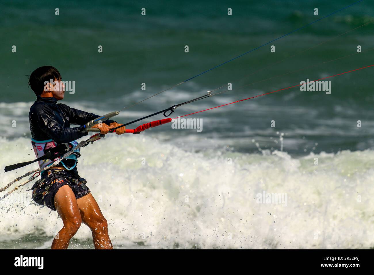 Un kitesurfer nelle onde al largo della spiaggia a Mui NE, Vietnam. Foto Stock