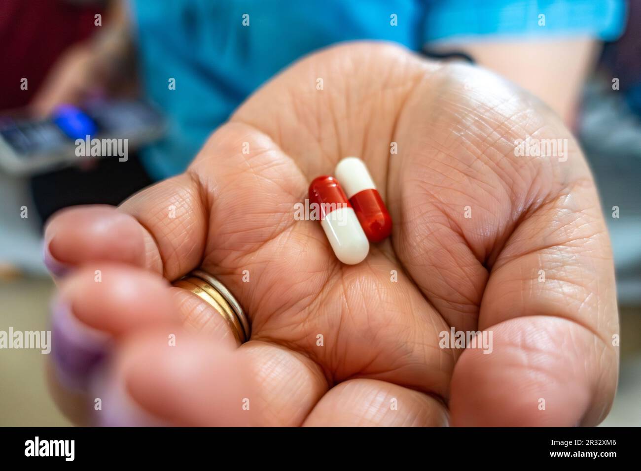 Una mano femmina che tiene capsule di paracetamolo rosse e bianche. Un assassino di dolore fuori dello scaffale. Foto Stock