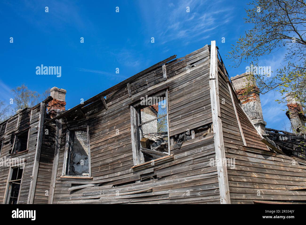 Casa in legno parzialmente bruciata contro il cielo blu nel distretto di Kopli di Tallinn, Estonia Foto Stock