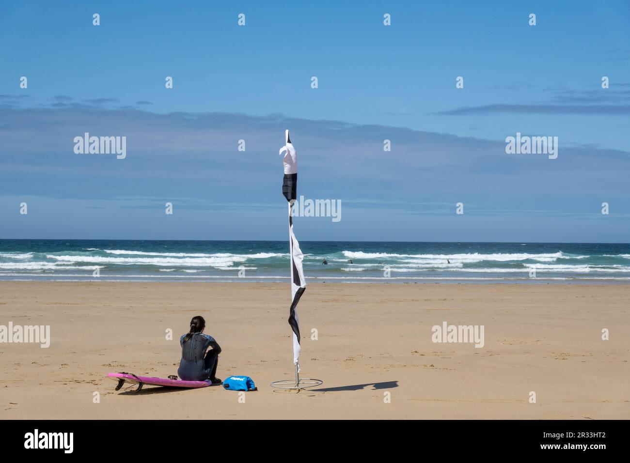 Perranporth, Regno Unito - 1st maggio 2023 : Un bagnino femminile sedette sulla spiaggia guardando il mare che aveva nuotatori e surfisti in acqua. Foto Stock