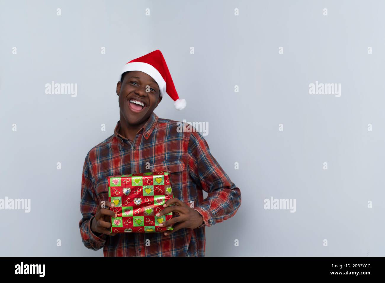 L'uomo africano sul cappellino di Natale che tiene i regali Foto Stock