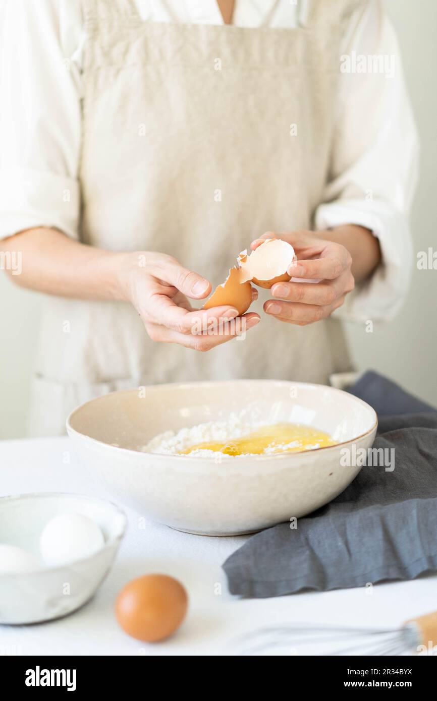 Cucinare le uova con le mani delle donne in una ciotola di farina. Fare una deliziosa colazione. Foto Stock