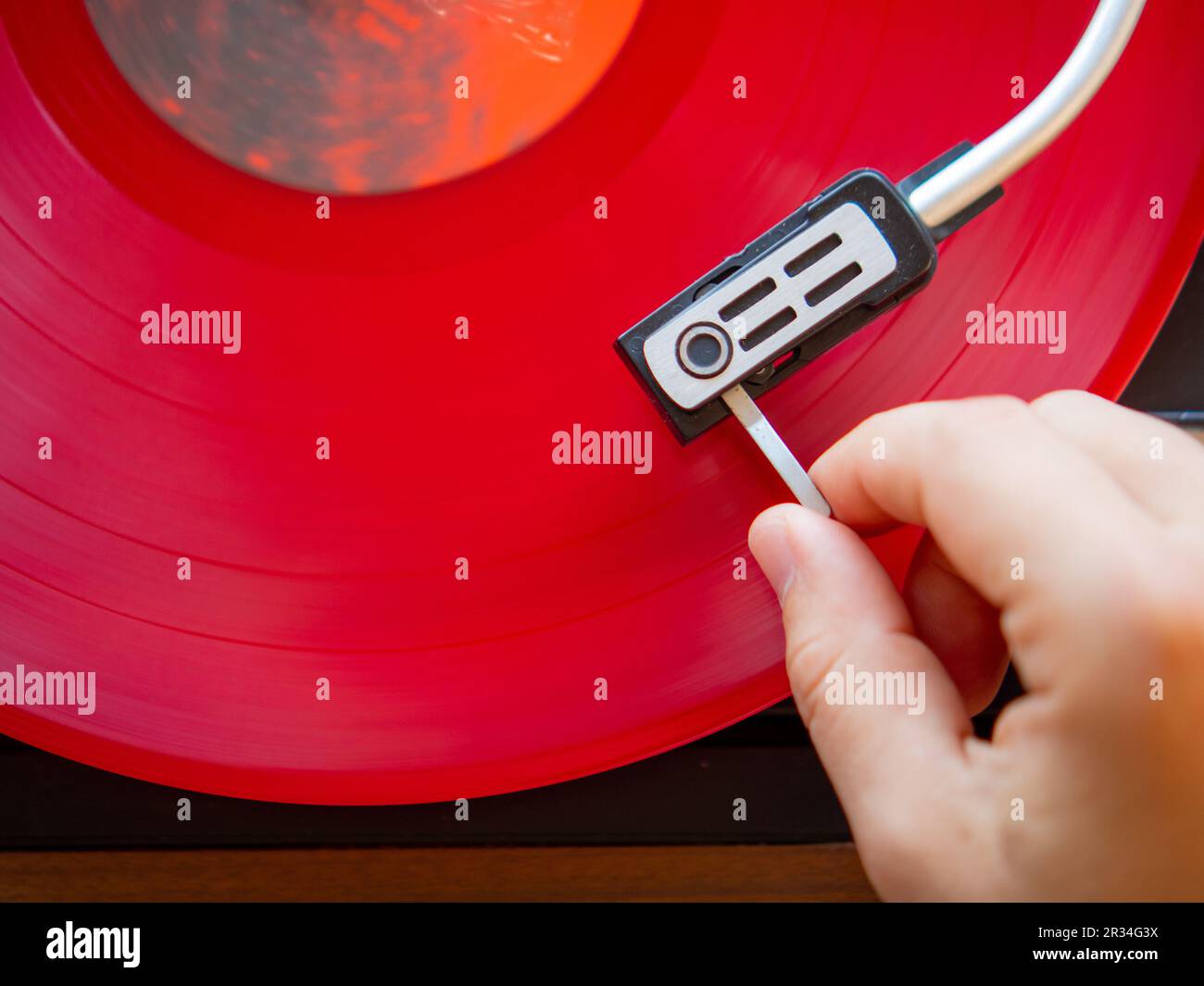 Dettaglio di una mano maschile che posiziona l'ago sulla traccia di un disco in vinile rosso. Giradischi vintage Foto Stock