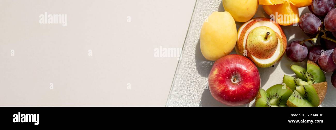 Materie frutti bacche platter, mango, arance e kiwi fragole, mirtilli pompelmo uva, banane mele sulla piastra bianca, sul bianco tabl Foto Stock
