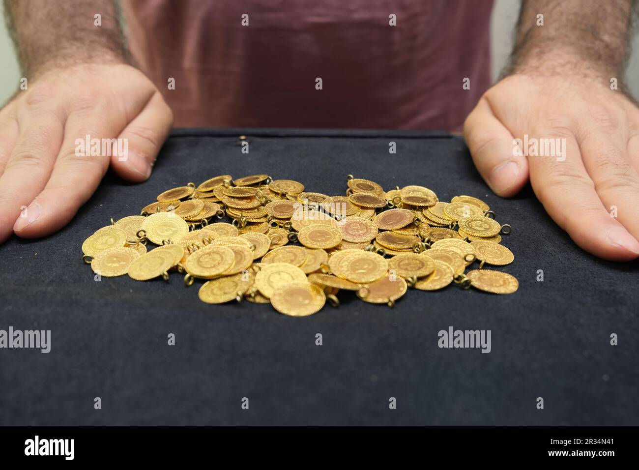 Monete d'oro turche con mani d'uomo su sfondo nero. Foto Stock