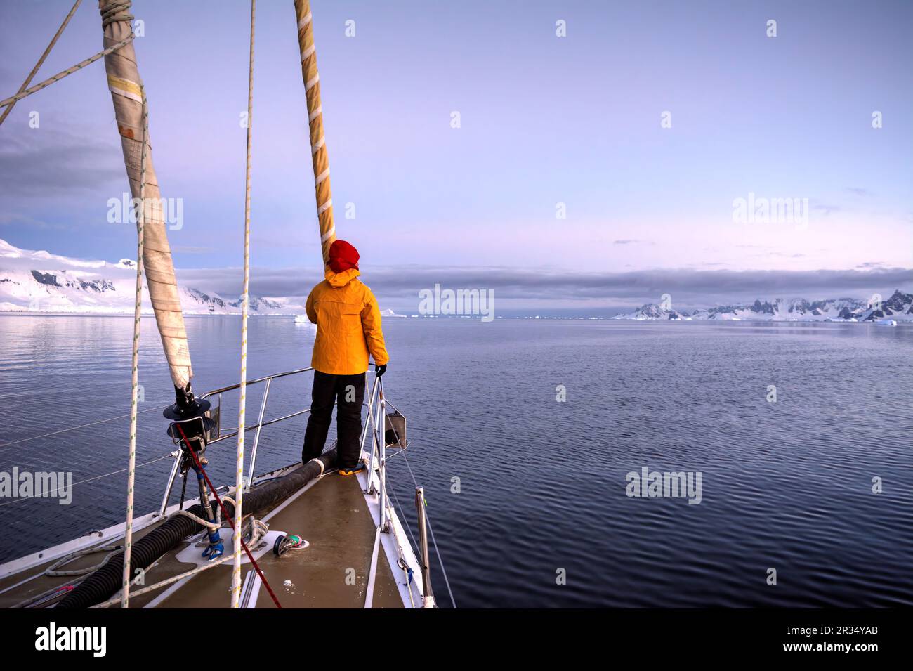 Un uomo viaggiatore si trova sulla prua di uno yacht a vela diretto per l'Antartide Foto Stock