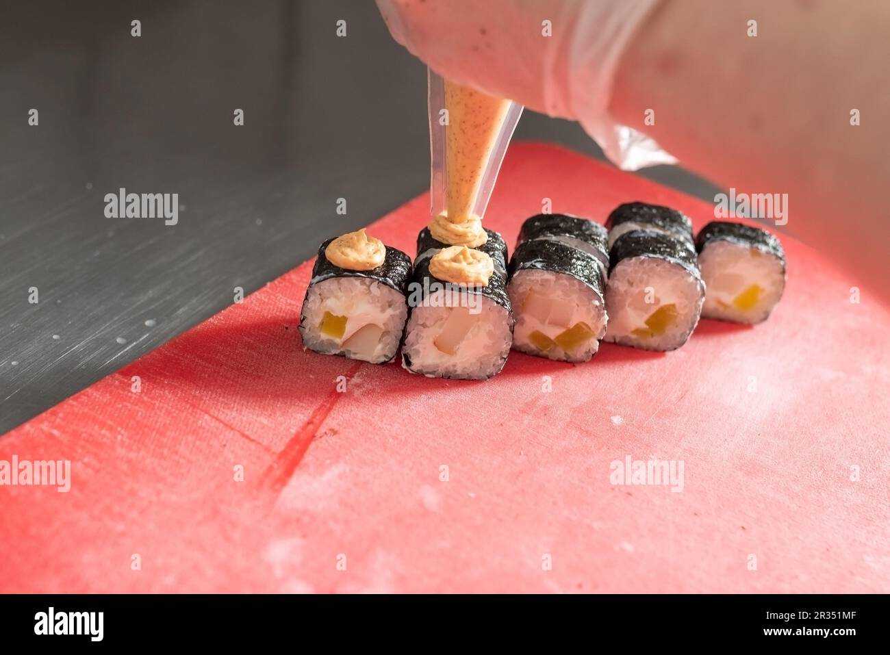 Applicazione di salsa piccante sul sushi con formaggio e daikon. Foto di alta qualità Foto Stock