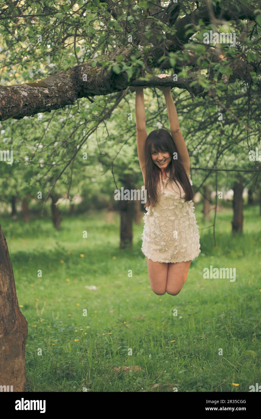 La ragazza si aggrappa a un ramo di albero Foto Stock