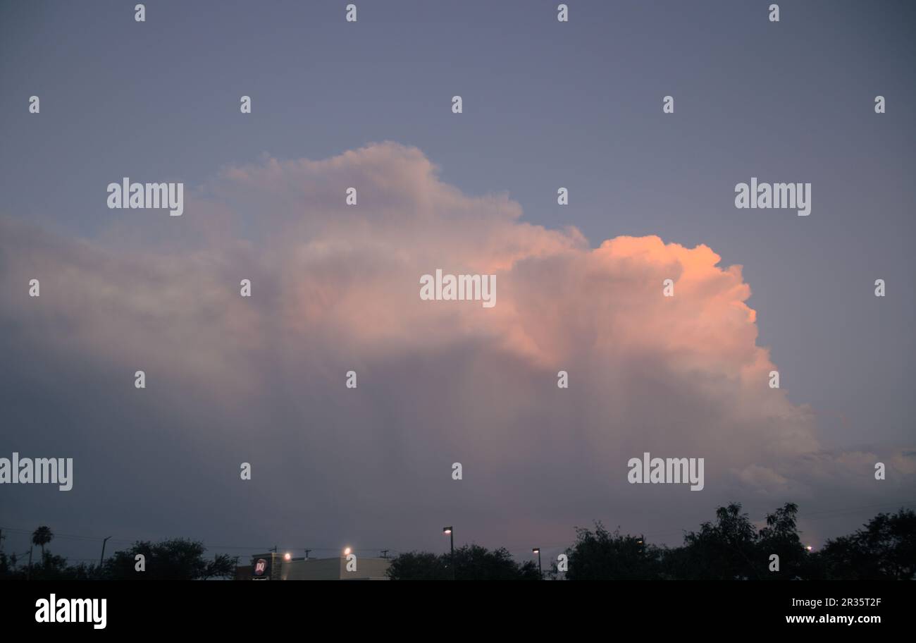 Una nuvola di temporale grave che muore al tramonto, causando bellissimi rossi e arance Foto Stock