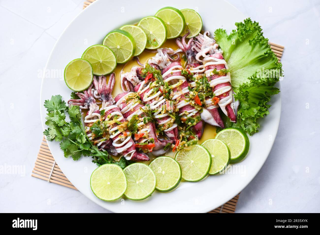 Calamari al vapore con peperoncino piccante al limone e calamari al limone al vapore con lime, piatti di pesce thailandesi con erbe e spezie - vista dall'alto Foto Stock