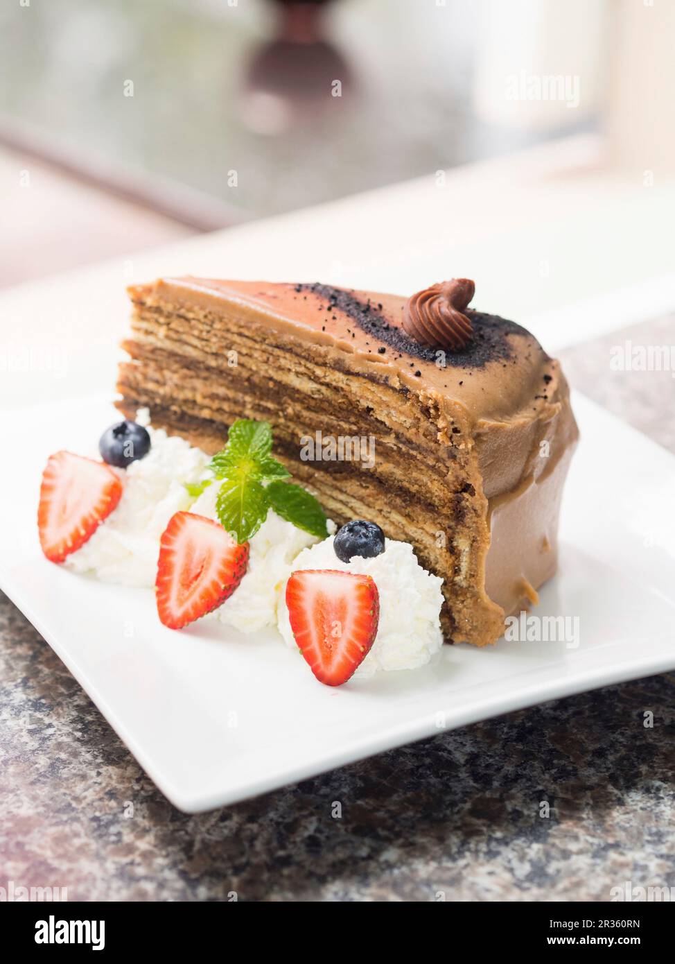 Una fetta di torta al cioccolato tiramisù servita con panna montata e frutti di bosco Foto Stock
