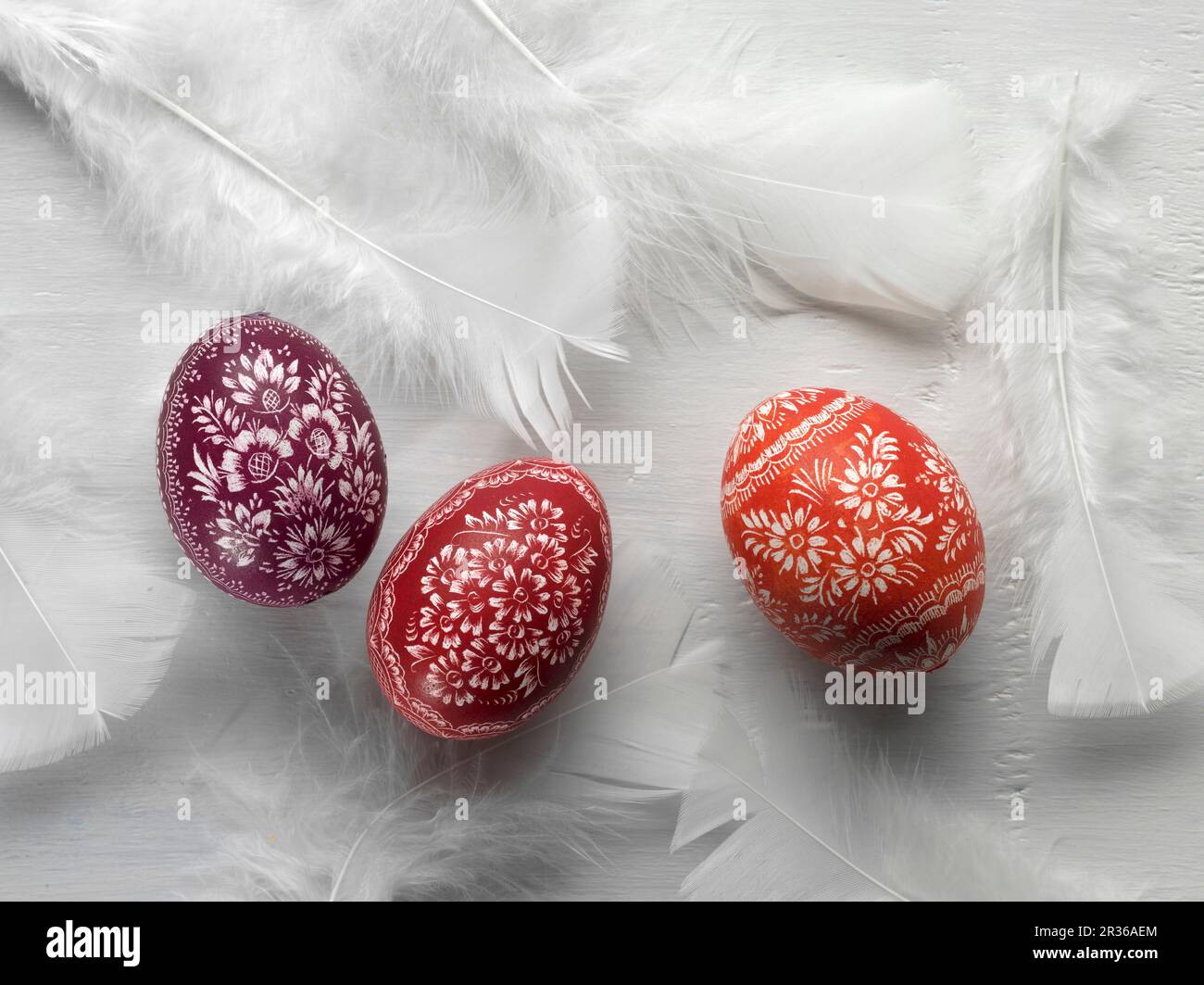 Uova di Pasqua sorbian e piume bianche su una superficie bianca Foto Stock