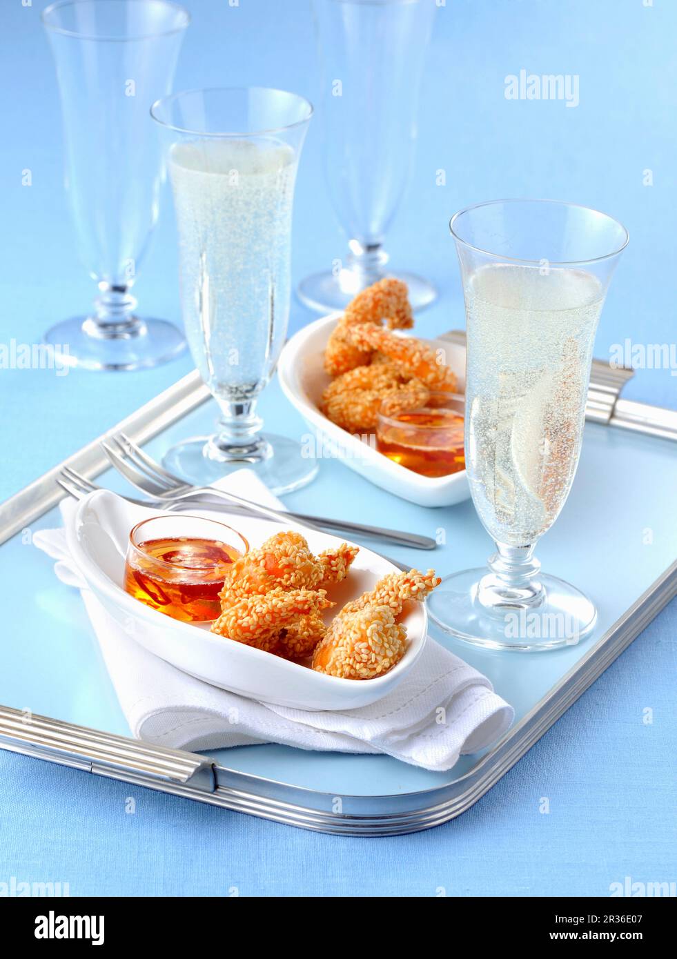 Fritti di semi di sesamo di gamberi con un tuffo di peperoncino e bicchieri di champagne Foto Stock