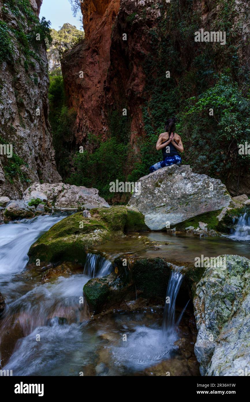 Donna che pratica yoga sul fiume, ponte di Dio, Akchour, Parco Naturale Talassettane, regione di Rif, marocco, africa. Foto Stock