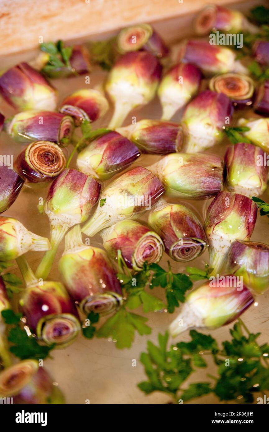 Carciofi e prezzemolo in una ciotola d'acqua Foto Stock