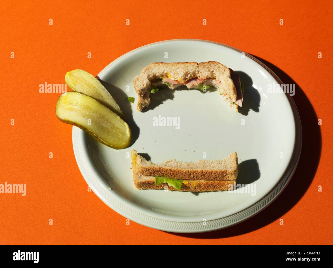Un sandwich New York Deli a metà pasto e una zucca affettata su un piatto bianco Foto Stock