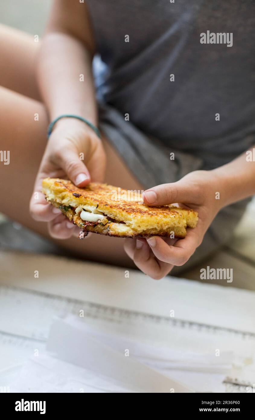 Mani che tengono la mozzarella in carrozza (un panino di mozzarella fritto italiano) Foto Stock