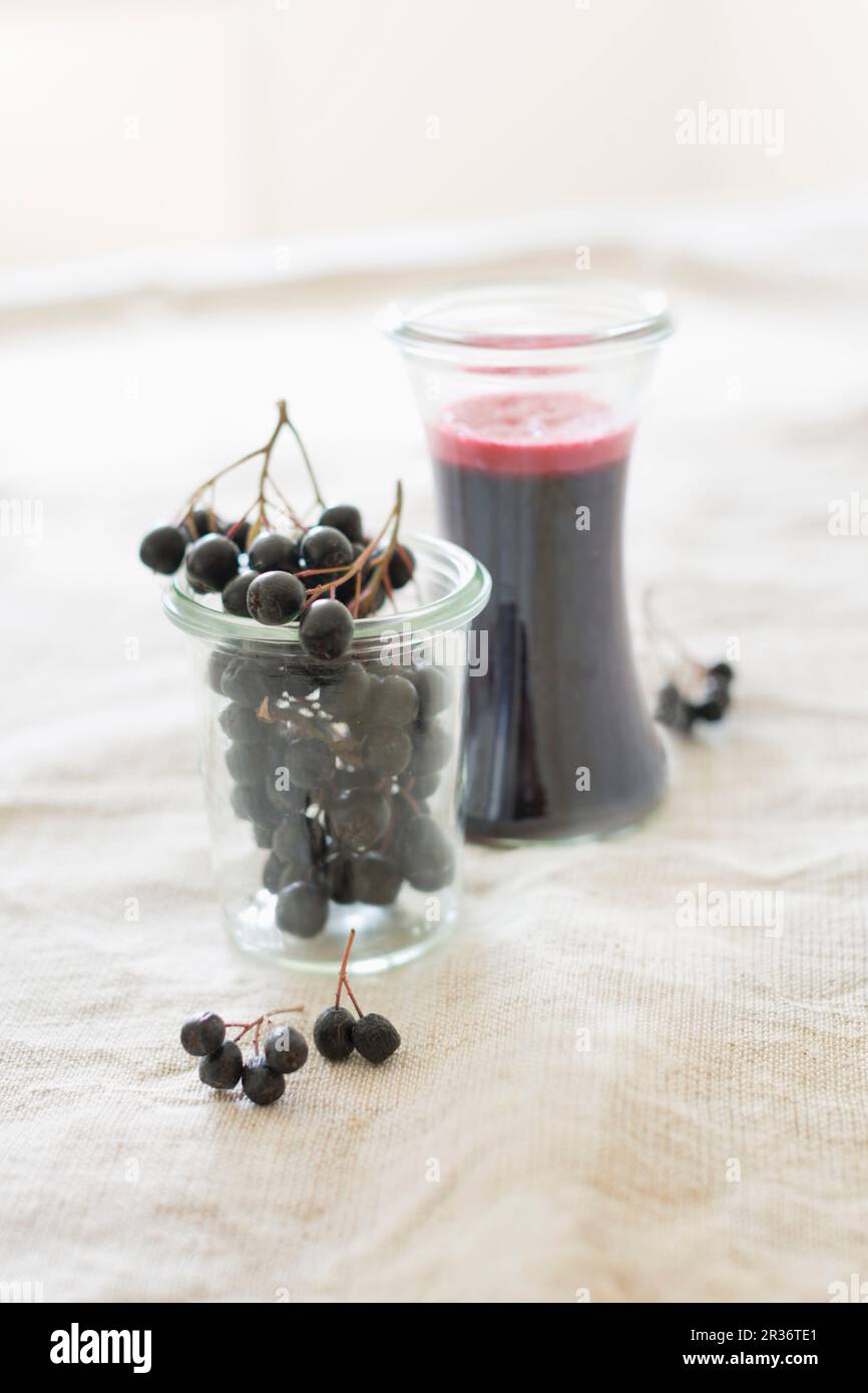 Fresche bacche di Aronia e fatti in casa a base di bacche di Aronia succo in bicchieri Foto Stock