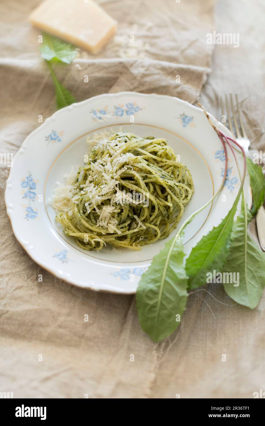 Spaghetti con fatti in casa a base di pesto di tarassaco, di foglie fresche di dente di leone e parmigiano su una tela di lino Foto Stock