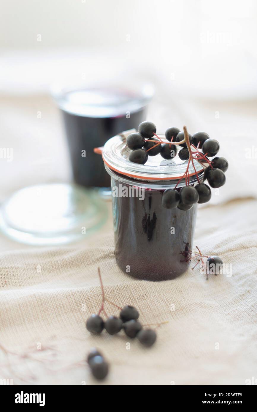 Gelatina di frutti di aronia fatta in casa in vasetti di vetro con frutti di aronia freschi Foto Stock