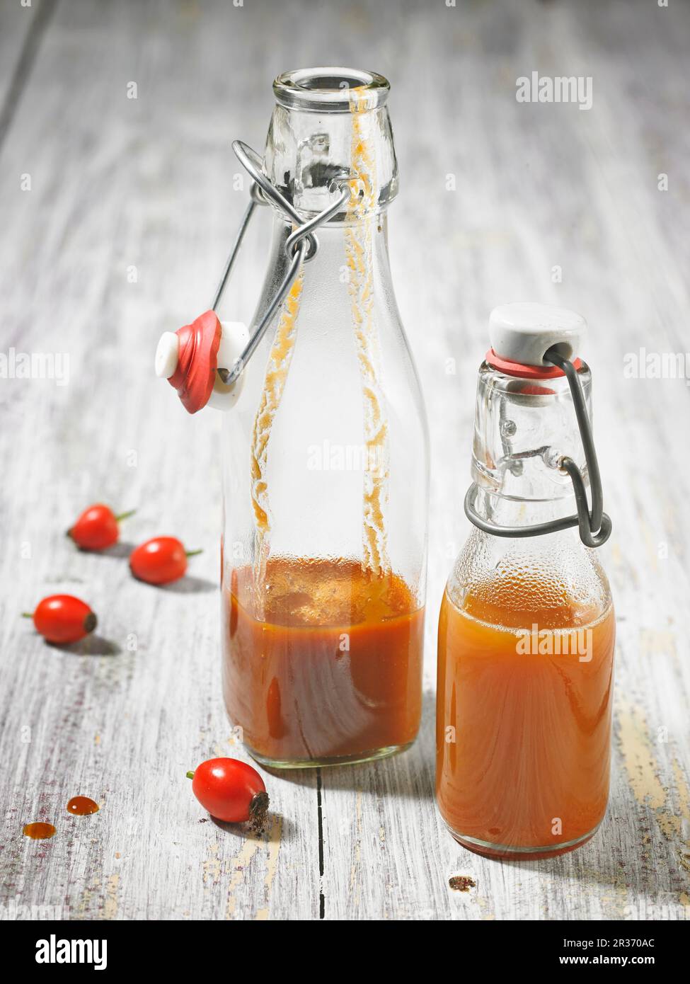 Succo d'anca di rose in due bottiglie con clip top parzialmente riempite Foto Stock