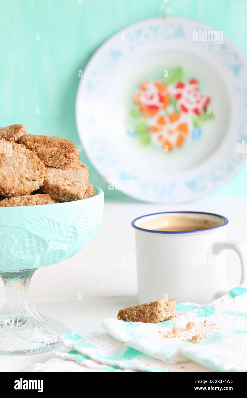 Una ciotola di biscotti senza glutine con farina di grano saraceno e zucchero a fiore di cocco e caffè in una tazza di smalto Foto Stock