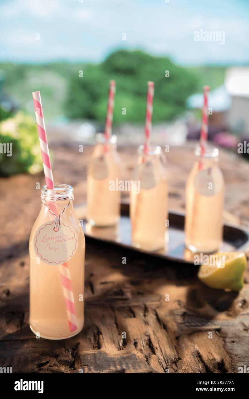 Cocktail di limone Melon in bottiglia con cannucce a righe rosa Foto Stock