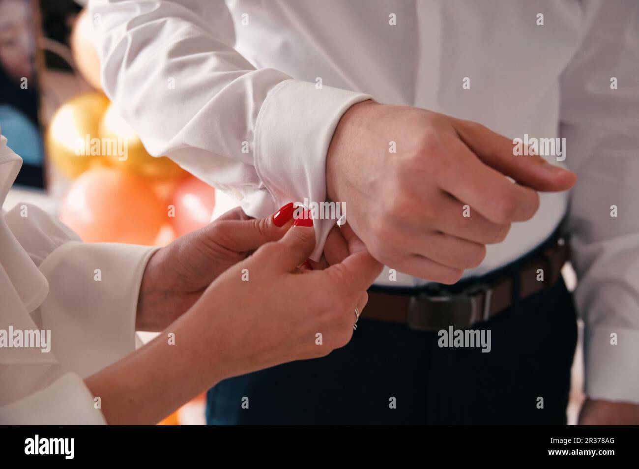 Foto ritagliata di mani femminili allacciare il bottone sul suo marito formale camicia Foto Stock