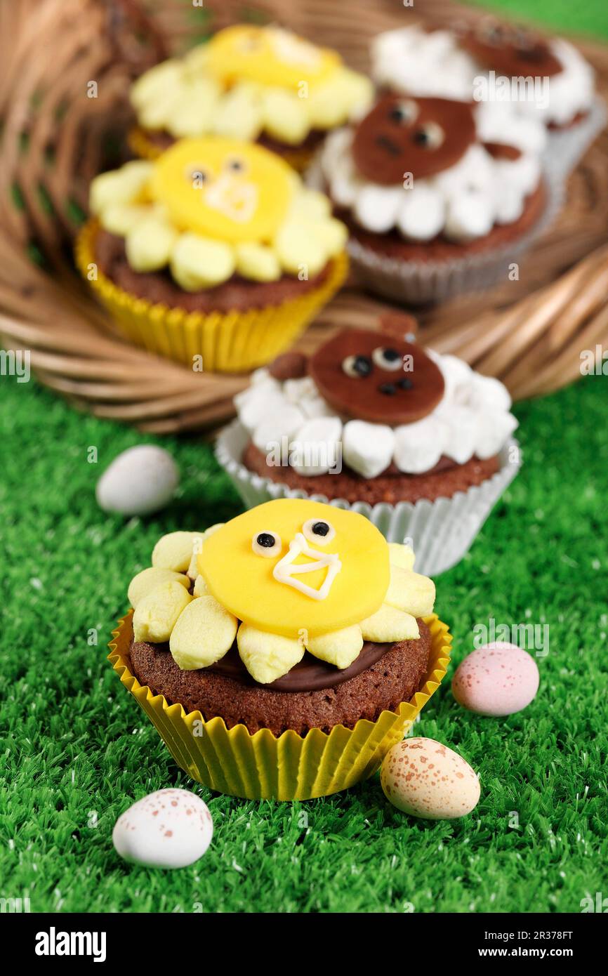 Cupcake a tema di animali di Pasqua su erba e in un cestino con mini uova di pasqua Foto Stock