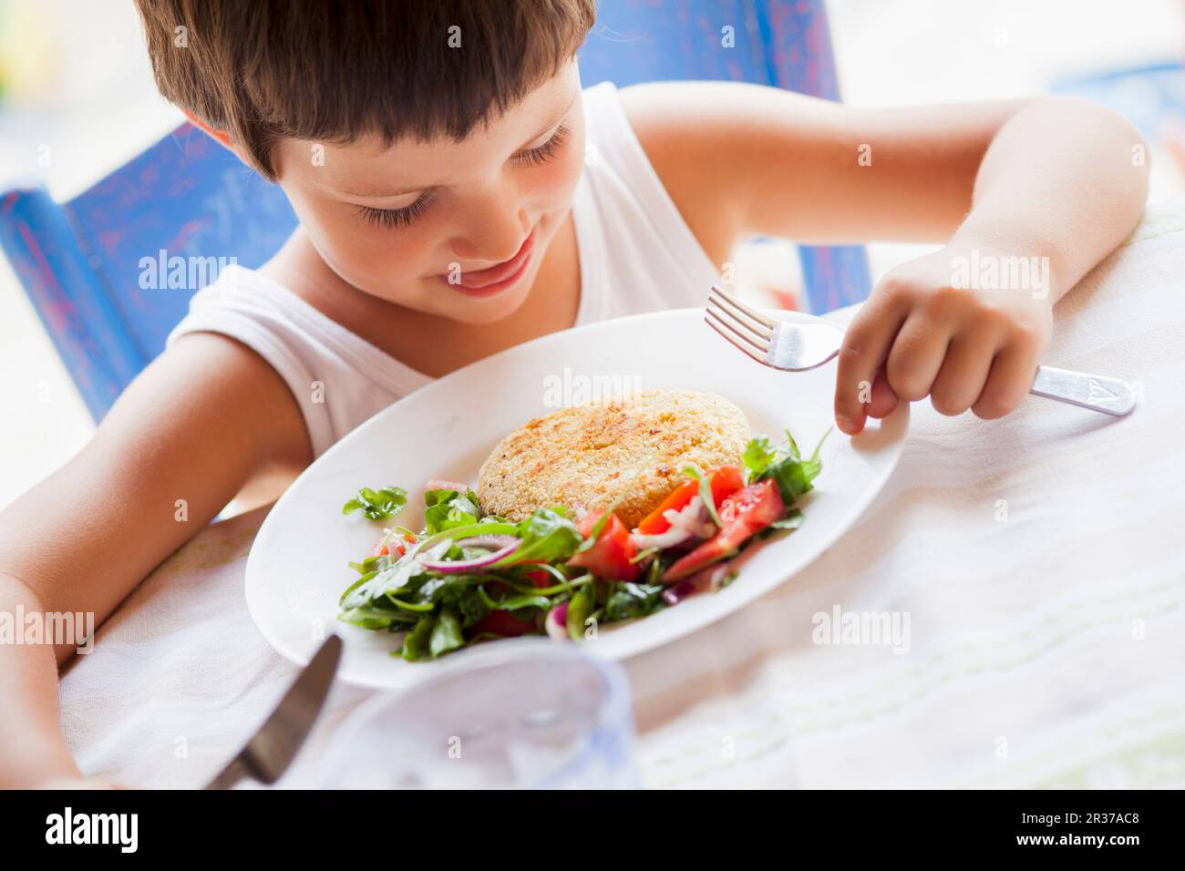 Un bambino mangiare polpette di ceci con insalata Foto Stock