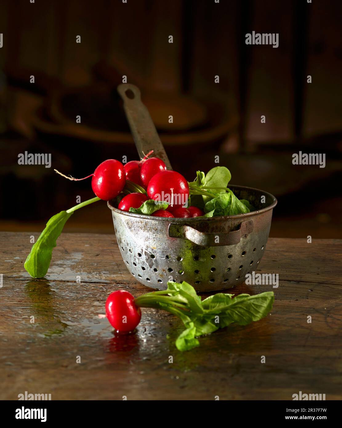 Ravanelli in e di fronte a un vecchio setaccio da cucina Foto Stock