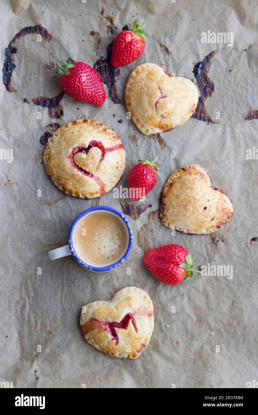 Torte di mano (mini torte) con un riempimento di fragola e decorazioni di cuore Foto Stock