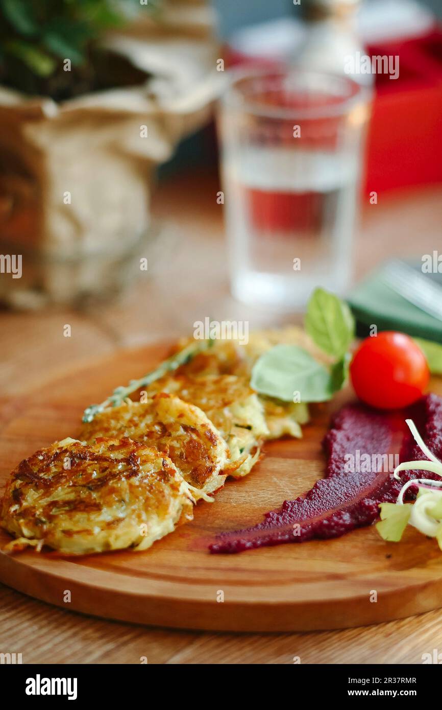 Patate e frittelle di verdure su un tagliere di legno Foto Stock