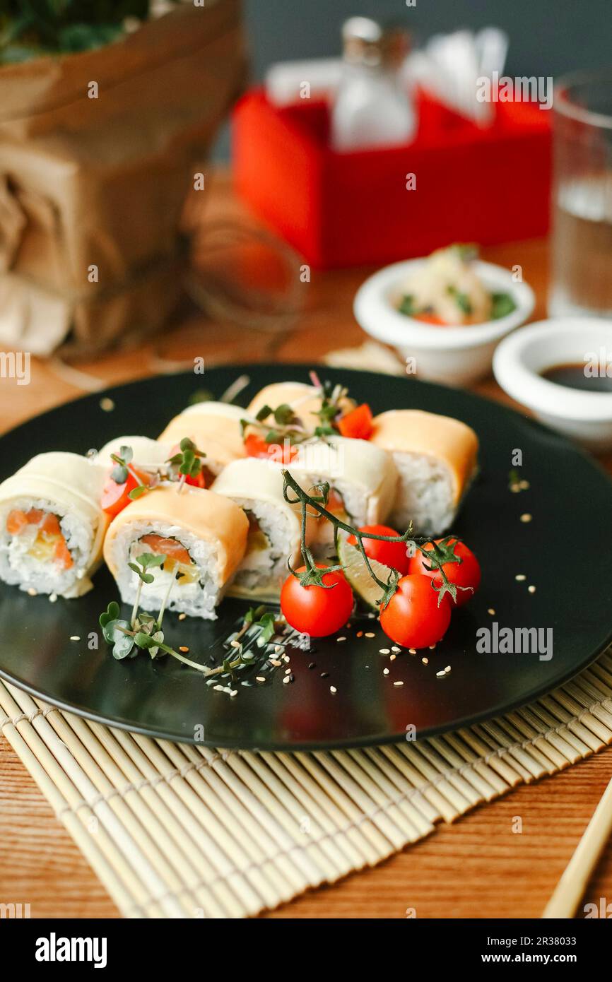 Sushi Rolls con salmone, formaggio fresco e pomodori cocktail Foto Stock