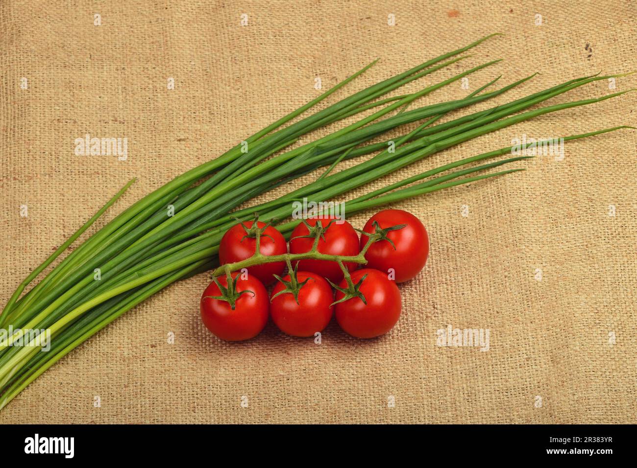 Mazzetto di pomodori ciliegini e cipollotti in tela Foto Stock