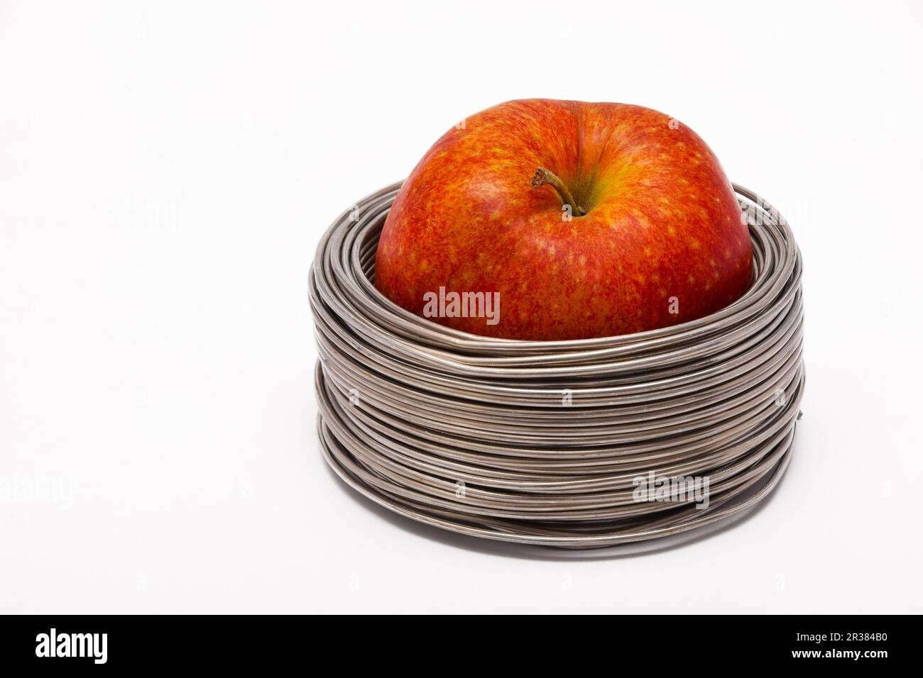 Cavo Apple: tutta la mela rossa in bobine di filo di alluminio isolato su sfondo bianco Foto Stock