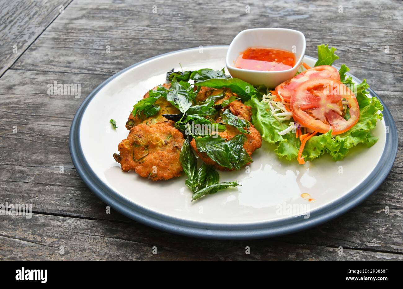 Piastra di gamberetti torte con insalata sul tavolo di legno Foto Stock