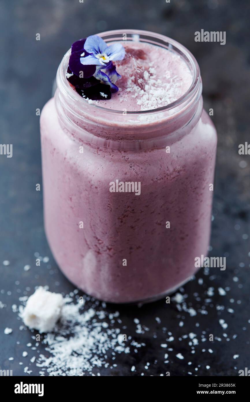 Frullato mirtillo con cocco e fiori commestibili Foto Stock