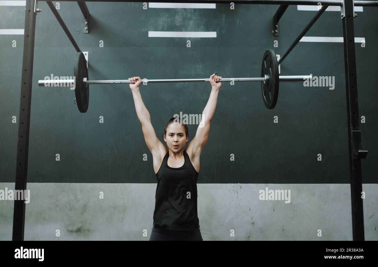 Sollevamento pesi, forte e ritratto di donna con barbell per ginnastica, esercizio fisico e allenamento intenso. Fitness, deadlift e body builder femminile Foto Stock
