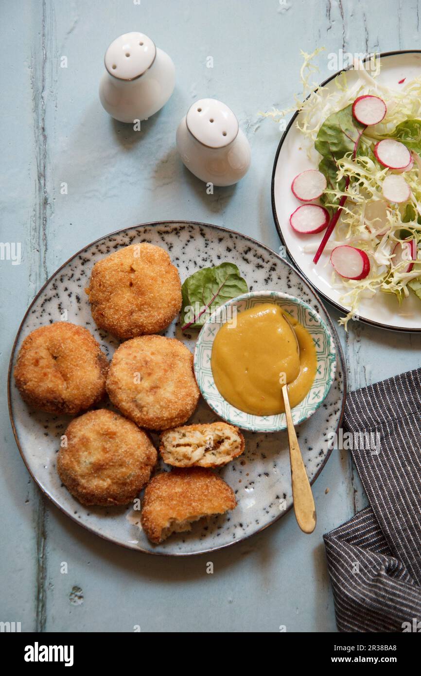 Torte di pesce servite con salsa e insalata Foto Stock
