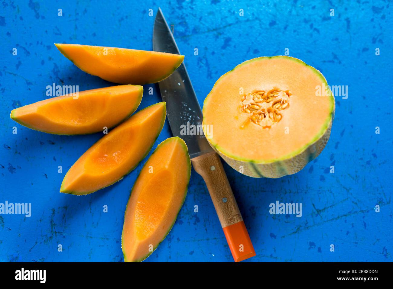 Mezzo melone di cantaloupe e cunei di melone con un coltello Foto Stock