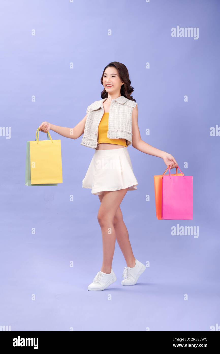 felice giovane donna sorridente con borse per lo shopping su sfondo viola Foto Stock