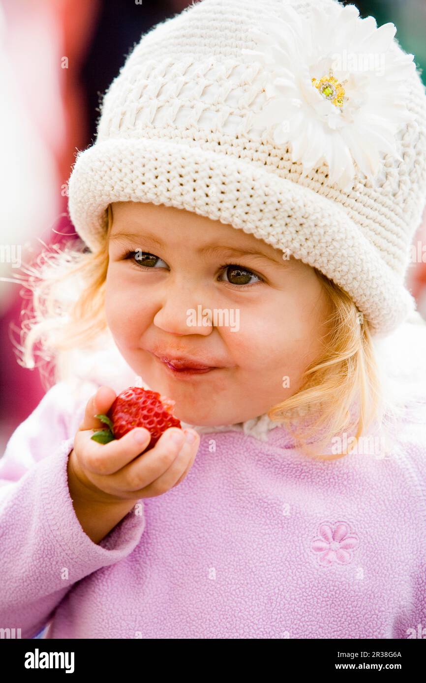 Bambina che si gode fragole fresche al mercato dei famers Foto Stock