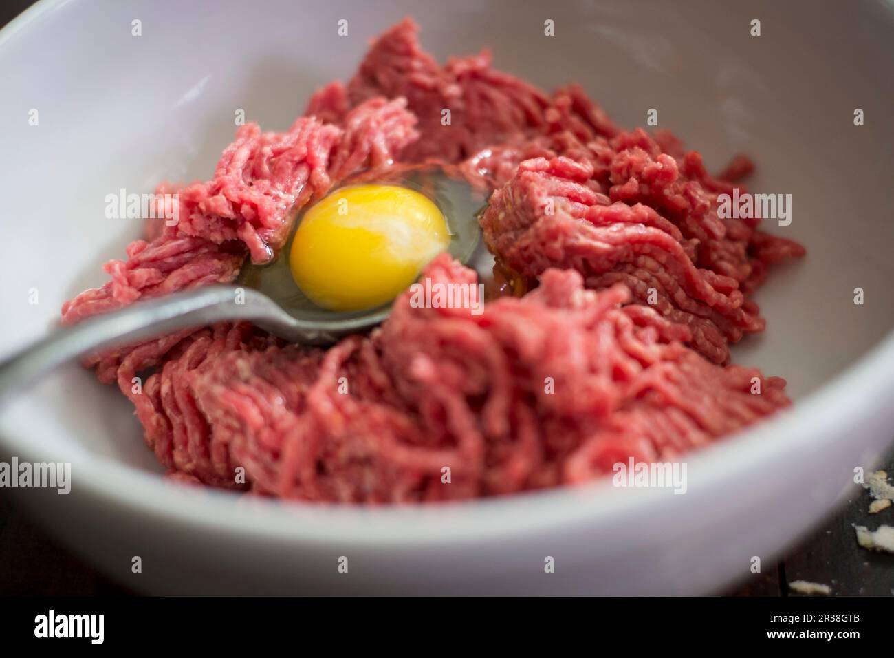 Ingredienti per polpette: Carne tritata e tuorlo d'uovo in un recipiente Foto Stock