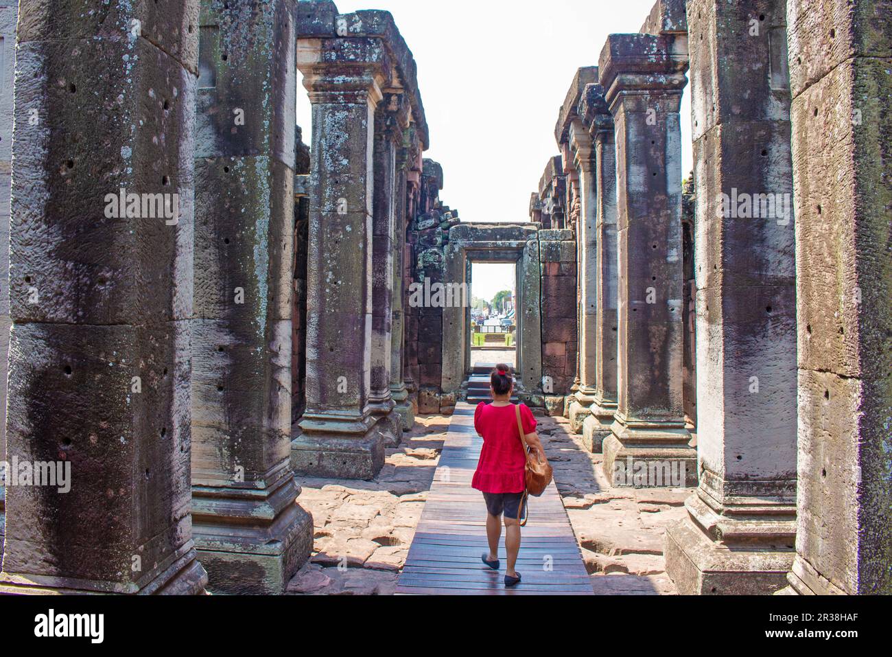 Camminando nel corridoio di Phi mai di alte colonne di pietra delle rovine del tempio di pietra Khmer Foto Stock