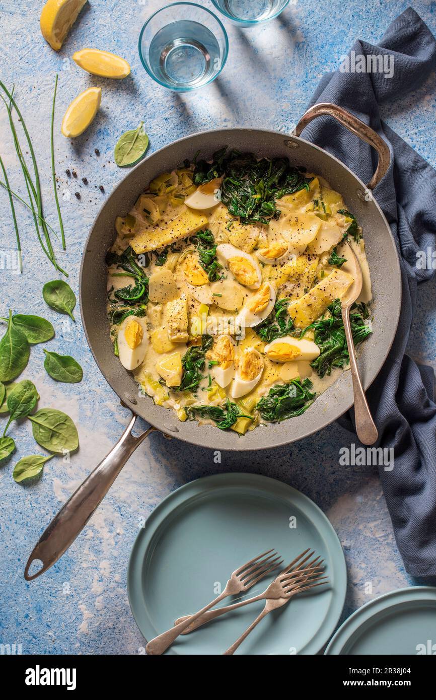 Un piatto da pentola, eglefino affumicato, patate a fette, porro, uova e stufato di spinaci Foto Stock