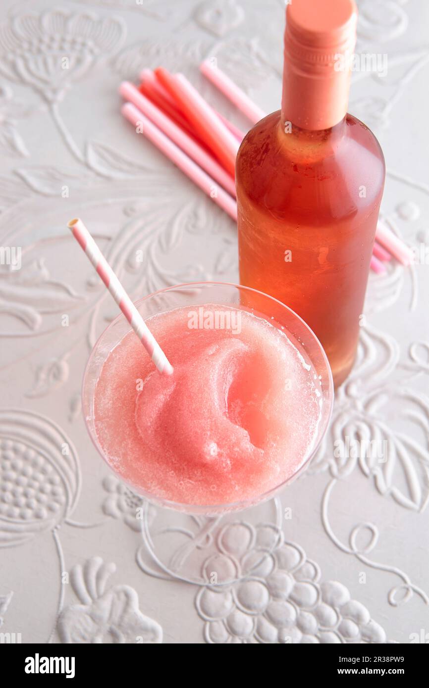 Un frosé in un bicchiere da cocktail con una bottiglia di vino rosato Foto Stock